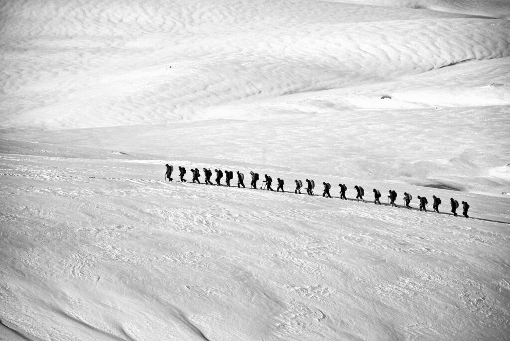 Silhouetted group hiking across a vast snowy landscape showcasing adventure and endurance.